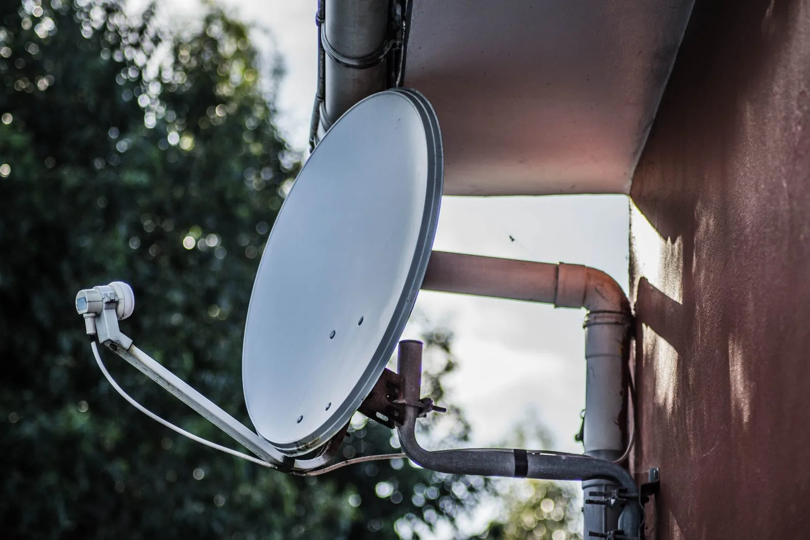 Technician rebuilding and securing a satellite dish mount on a roof